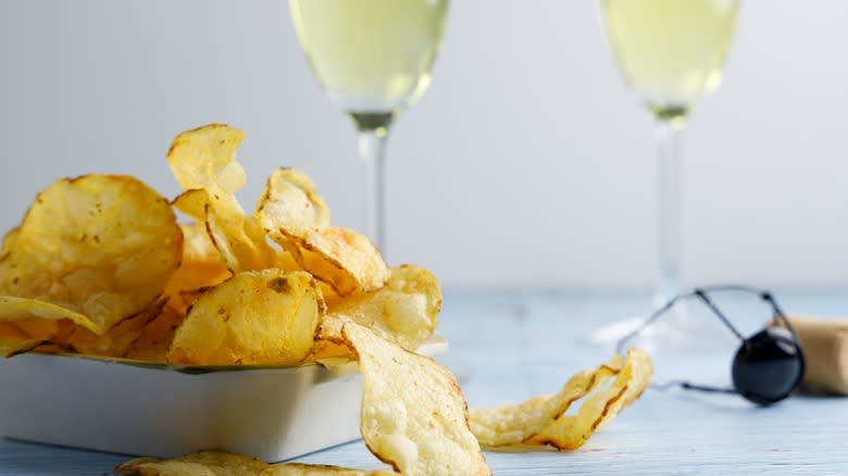 A bowl of potato chips with two champagne flutes