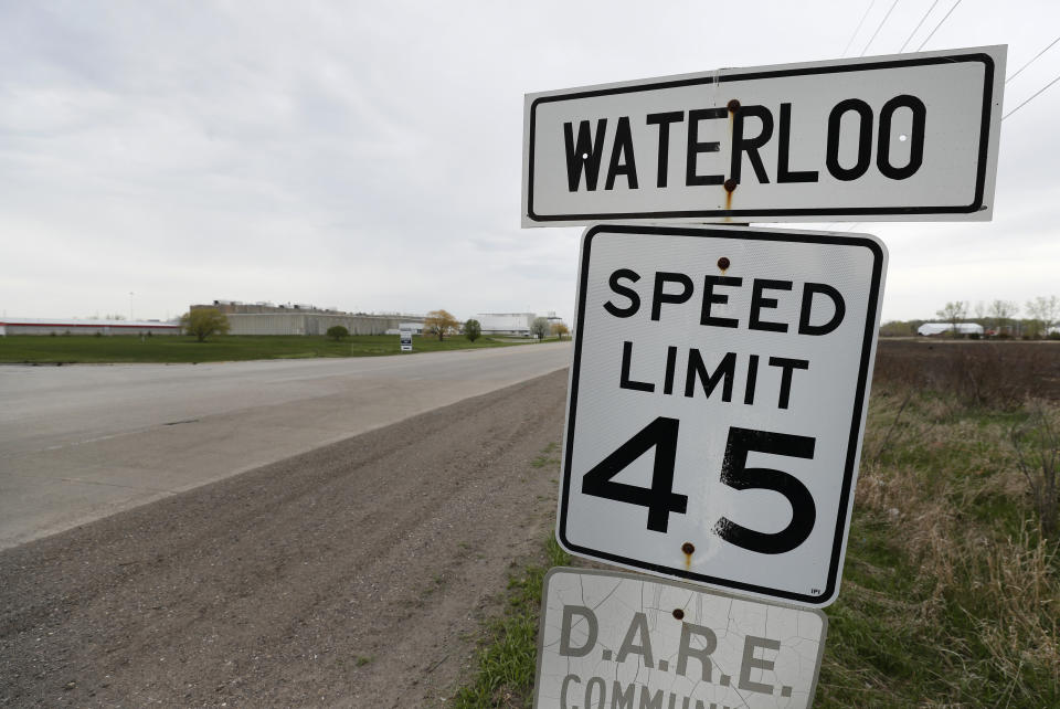 In this Friday, May 1, 2020, photo, a city of Waterloo sign sits across the road from the Tyson Foods plant in Waterloo, Iowa. Local Waterloo officials blame Tyson for endangering not only its workers and their relatives during the pandemic but everyone else who leaves home to work or get groceries. They are furious with the state and federal governments for failing to intervene — and for pushing hard to reopen the plant days after public pressure helped shut it down. (AP Photo/Charlie Neibergall)