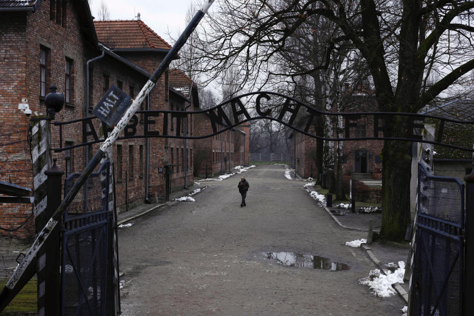 Una persona pasa cerca de la puerta del antiguo campo de concentración y extermino nazi de Auschwitz-Birkenau, con la frase ''Arbeit Macht Frei" ("El trabajo os hará libres"), en Oswiecim, Polonia, el 26 de enero de 2023. (AP Foto/Michal Dyjuk)