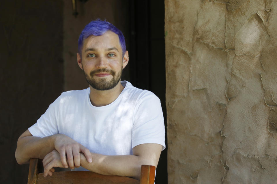 In this Monday, March 30, 2020, photo Luke Blaine stands at the front entrance of his home in Phoenix. Blaine, 30, a bartender at Fez, a popular restaurant in downtown Phoenix, was laid off with the rest of the staff when the business shut completely to follow Arizona’s state precautions amid the pandemic. Blaine said he was blessed to have been taught the value of a dollar by his parents and was entering unemployment without any debt. (AP Photo/Ross D. Franklin)