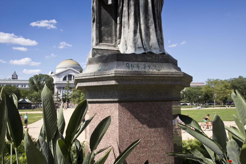 Green paint is seen on the pedestal of the statue of Joseph Henry, outside the headquarters of the Smithsonian Institution on the National Mall in Washington, Monday, July 29, 2013. U.S. Park police say the marring of the Smithsonian's first secretary was discovered on July 26, the same day that the Lincoln Memorial was splattered with green paint. The Smithsonian's Museum of Natural History is seen in the distance. (AP Photo/J. Scott Applewhite)