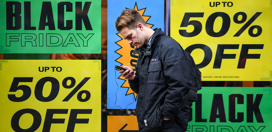 man on the phone in front of Black Friday ads