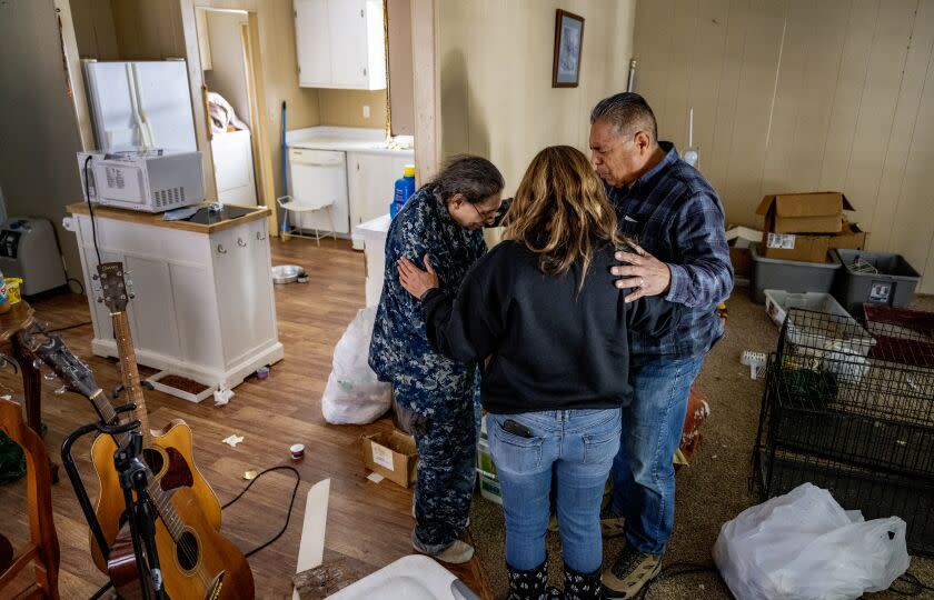 VALLEY OF ENCHANTMENT, CA - MARCH 24, 2023: Volunteers with Operation Mountain Strong Rita Nelson, middle, and Pastor Sal Martinez pray for Virginia Hauser, 70, left, whose trailer has partially collapsed but she refuses to leave her 11 cats in the Valley of Enchantment on March 24, 2023 in San Bernardino Mountains, California. Hauser's trailer was badly damaged under the weight of the recent heavy snowfalls. Operation Mountain Strong is trying to find homes for Houser's cats and also a safer place for her live. The organization brought her food and also food for her cats.(Gina Ferazzi / Los Angeles Times)