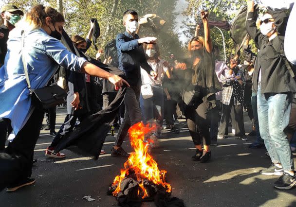 PHOTO: Iranian protesters set their scarves on fire while marching down a street in Tehran on Oct. 1, 2022. (Getty Images)