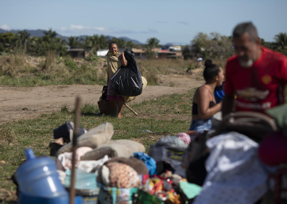 A woman carries her belongings during an eviction at a settlement coined the "First of May Refugee Camp," named for the date people moved on the land designated for a Petrobras refinery, in Itaguai, Rio de Janeiro state, Brazil, Thursday, July 1, 2021, amid the new coronavirus pandemic. (AP Photo/Silvia Izquierdo)