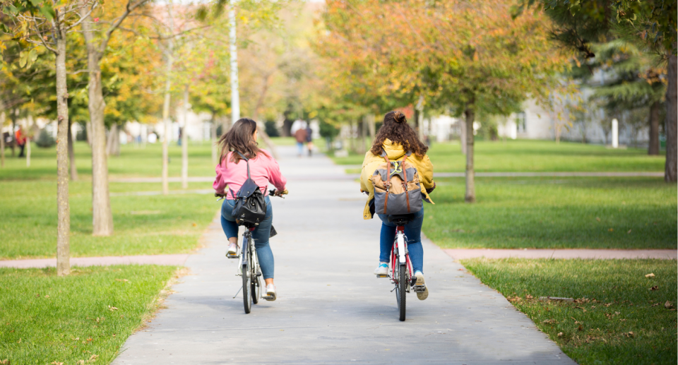Two girls riding bikes into school. Photo: Getty