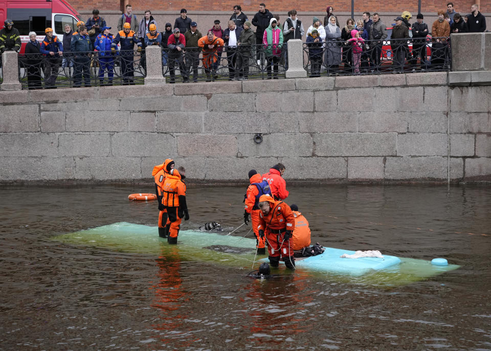 Emergency responders work to recover victims of a bus crash in St. Petersburg, Russia, Friday, May 10, 2024. Authorities in St. Petersburg say that at least one person died and five others were hospitalized with injuries when a bus fell off a bridge in St. Petersburg. (AP Photo/Dmitri Lovetsky)