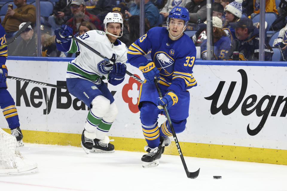 Buffalo Sabres defenseman Ryan Johnson (33) carries the puck past Vancouver Canucks center Teddy Blueger (53) during the second period of an NHL hockey game Saturday, Jan. 13, 2024, in Buffalo, N.Y. (AP Photo/Jeffrey T. Barnes)