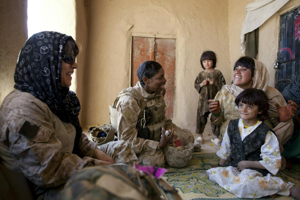 BOLDOC, AFGHANISTAN - NOVEMBER 23: (SPAIN OUT, FRANCE OUT, AFP OUT) Master Sargent Cherelle Peters-Williams, US Marine with the FET (Female Engagement Team) 1st Battalion 8th Marines, Regimental Combat team II speaks with an Afghan woman and her family during a village medical outreach on November 23, 2010 in Boldoc, in Helmand province, Afghanistan. There are 48 women presently working along the volatile front lines of the war in Afghanistan deployed as the second Female Engagement team participating in a more active role, gaining access where men can't. The women, many who volunteer for the 6.5 month deployment take a 10 week course at Camp Pendleton in California where they are trained for any possible situation, including learning Afghan customs and basic Pashtun language. (Photo by Paula Bronstein/Getty Images)