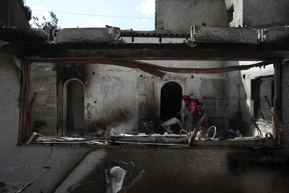 A member of a rescue team searches a burned house in Mati, east of Athens, Wednesday, July 25, 2018. Rescue crews were searching Wednesday through charred homes and cars for those still missing after the deadliest wildfires to hit Greece in decades decimated seaside areas near Athens, killing at least 79 people and sending thousands fleeing. (AP Photo/Thanassis Stavrakis)