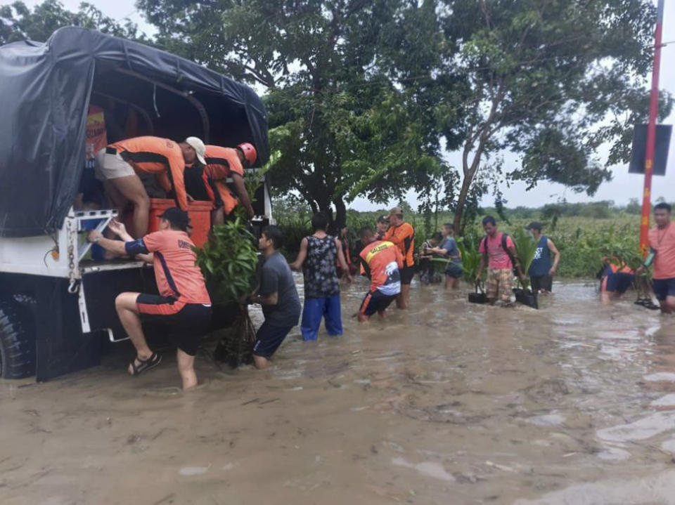 In this handout photo provided by the Philippine Coast Guard, rescuers help residents move to safer grounds in Tuguegarao, Cagayan province, northern Philippines on Tuesday Aug. 23, 2022. A tropical storm lashed the northern Philippines with strong wind and rain Tuesday, injuring at least two people and prompting the president to close schools and government offices in the capital and outlying provinces. (Philippine Coast Guard via AP)