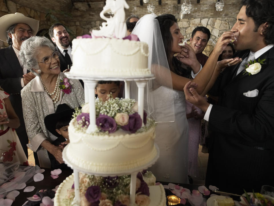 married couple shoving cake in each other's faces as family looks on
