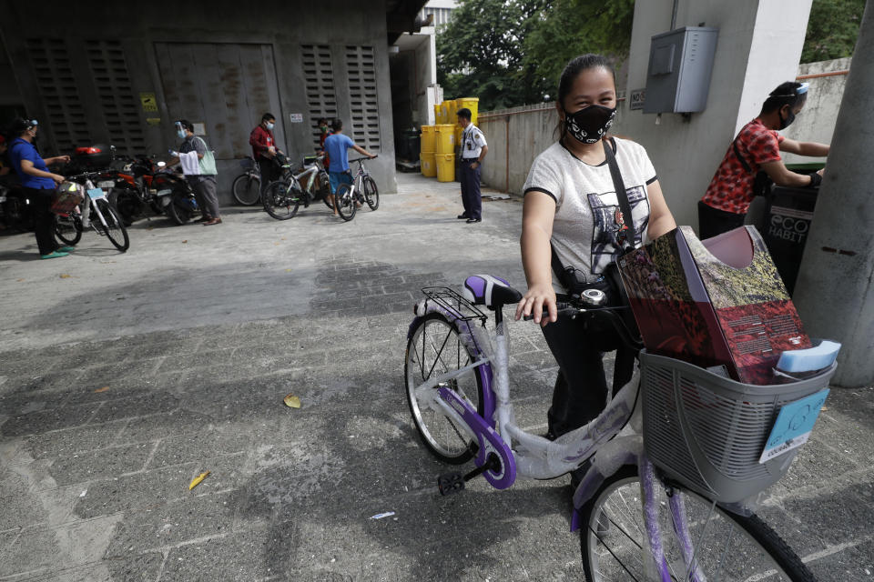 A recipient of a bicycle from the Benjamin Canlas Courage to be Kind Foundation pushes her bicycle outside a building at the financial district of Manila, Philippines, Saturday, July 11, 2020. Restricted public transportation during the lockdown left many Filipinos walking for hours just to reach their jobs. The foundation saw the need and gave away mountain bikes to nominated individuals who are struggling to hold on to their jobs in a country hard hit by the coronavirus. (AP Photo/Aaron Favila)