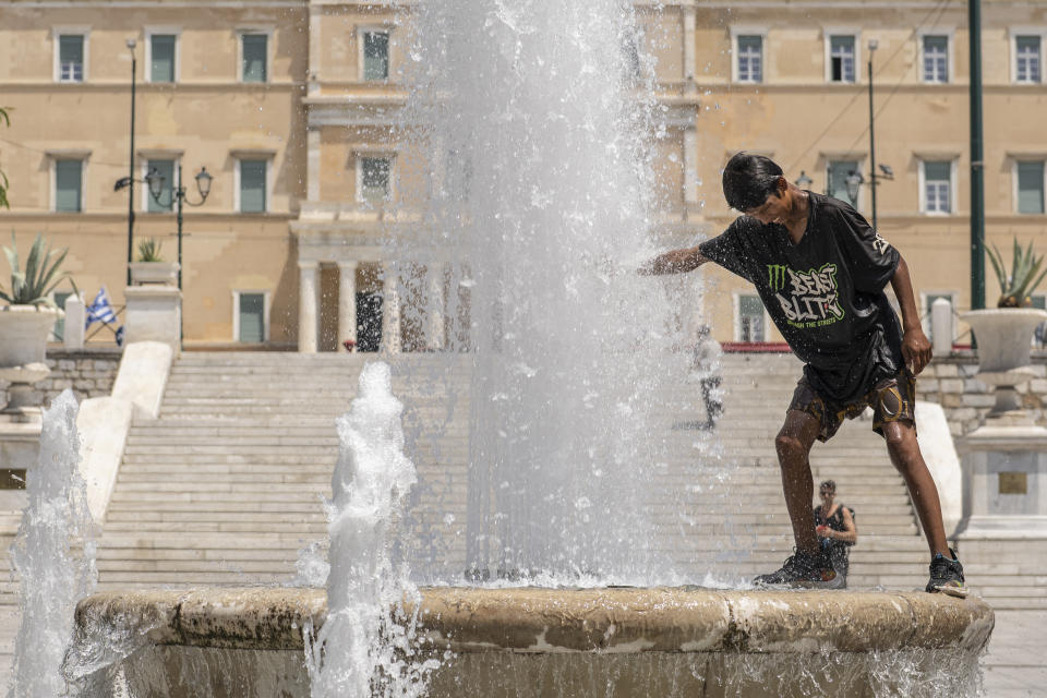 A boy cools himself in a fountain of the central Syntagma square in front of the Greek parliament during a hot day in Athens, Friday, July 14, 2023. Temperatures were starting to creep up in Greece, where a heatwave was forecast to reach up to 44 degrees Celsius in some parts of the country over the weekend. (AP Photo/Petros Giannakouris)