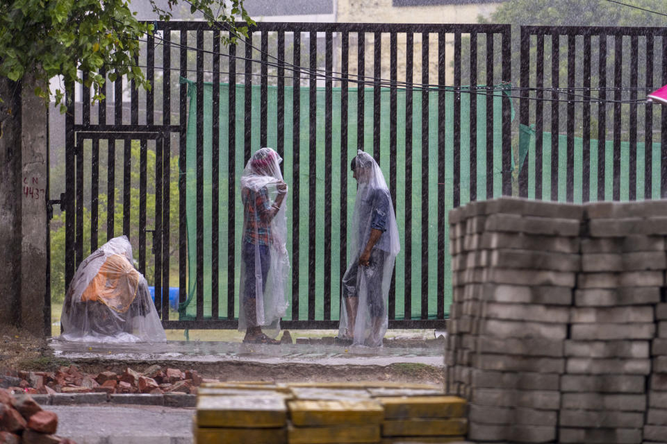 People stand covered in plastic sheets as it rains in New Delhi Thursday, June 30, 2025. India's monsoon season runs from June to September. (AP Photo/Rajesh Kumar Singh)
