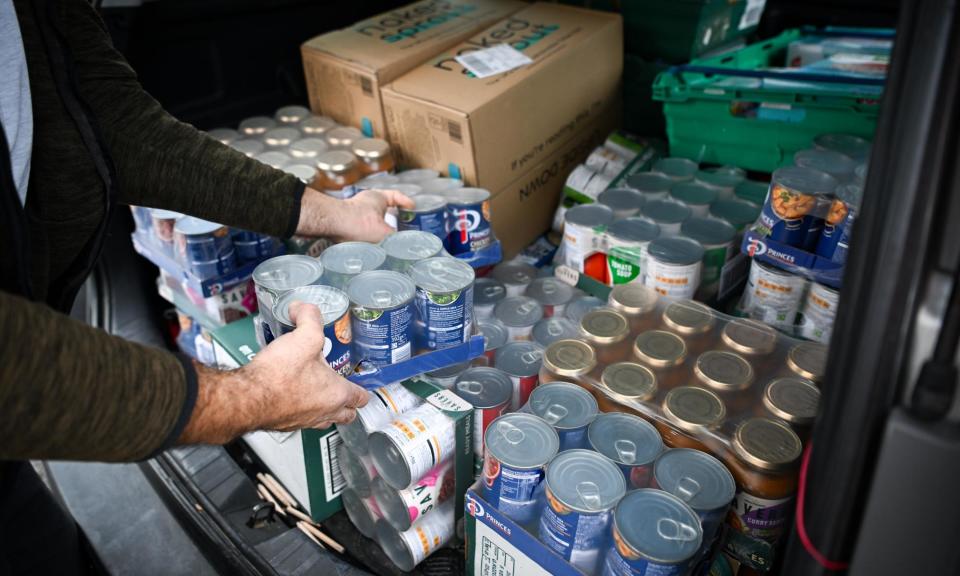 <span>A volunteer loads up a car at a food bank distribution hub.</span><span>Photograph: Getty</span>