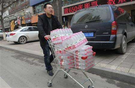 A man pushes a shopping cart filled with bottled waters after reports on heavy levels of benzene in local tap water, in Lanzhou, Gansu province April 11, 2014. REUTERS/Stringer