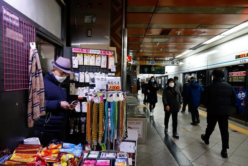 A man wearing a mask uses his mobile phone at his kiosk at a subway station amid the coronavirus disease (COVID-19) pandemic in Seoul