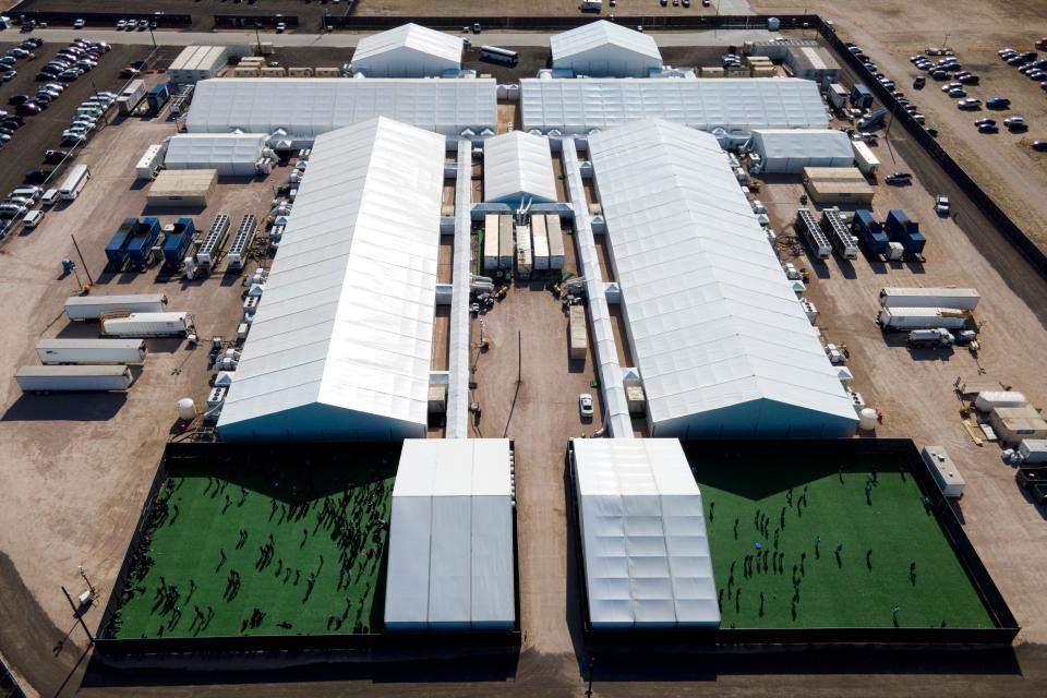 Migrants are seen in a green area outside of a soft-sided detention center after they were taken into custody while trying enter the U.S., in Donna, Texas on March 19, 2021. The Donna facility consists of large interconnected tents with enclosed outdoor areas where children can go. But lawyers who have interviewed children detained at Donna say some can go days without being allowed outside.