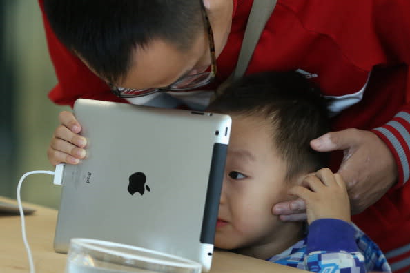 A Chinese customer and his son look at the iPad in the newly opened Apple Store in Wangfujing shopping district on October 20, 2012 in Beijing, (Photo by Feng Li/Getty Images)