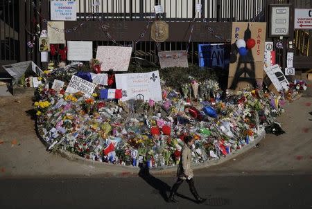 A television reporter walks past the entrance to the French embassy, adorned with flowers and expressions of sympathy, in Washington November 16, 2015. REUTERS/Carlos Barria