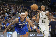 Milwaukee Bucks forward Khris Middleton (22) passes the ball past Orlando Magic forward Paolo Banchero (5) during the first half of an NBA basketball game, Sunday, April 14, 2024, in Orlando, Fla. (AP Photo/John Raoux)