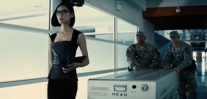 Mercy Graves walking with army soldiers down a hallways with a silver case in "Batman v Superman: Dawn of Justice"