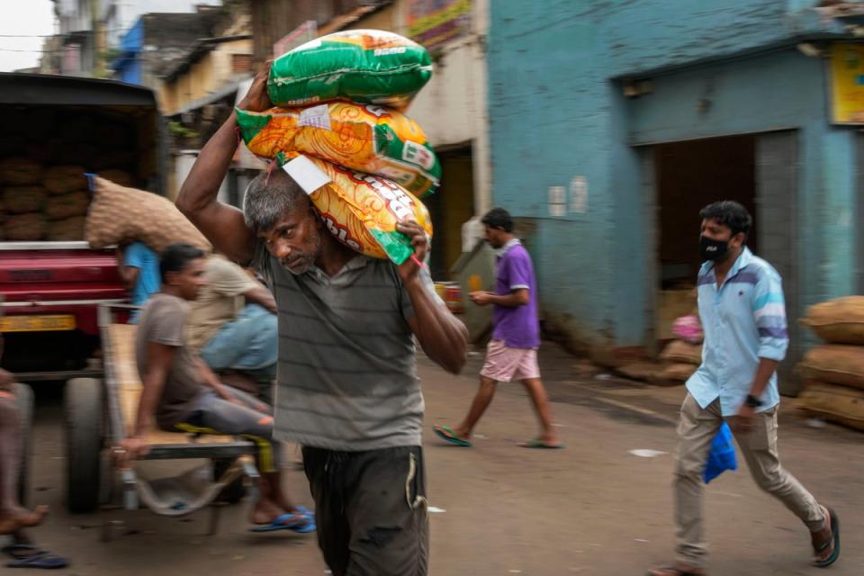 A porter carries sacks of imported food items at a market place in Colombo (AP)