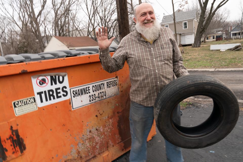 Patrick DeLapp, vice president of Tennsee Town, picks up a tire someone left by a dumpster off S.W. Buchanan Avenue Tuesday morning.