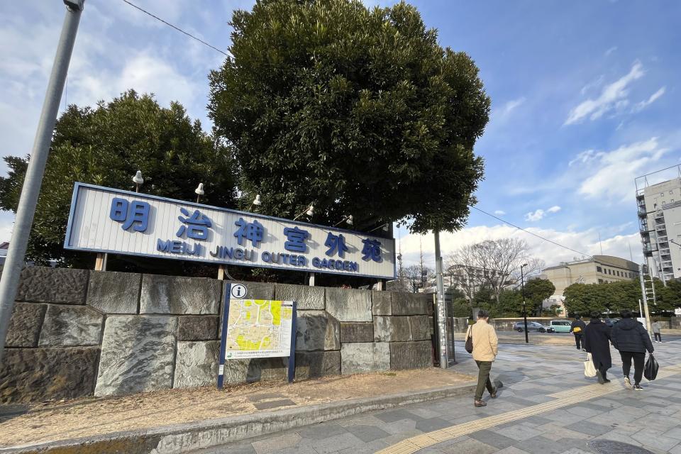 People walk past the sign of Tokyo's Jingu Gaien park Saturday, Jan. 13, 2024. Tokyo Gov. Yuriko Koike was asked to suspend a disputed $2.45 billion project to convert the beloved park district into a largely commercial area anchored around three skyscrapers. (AP Photo/Stephen Wade)