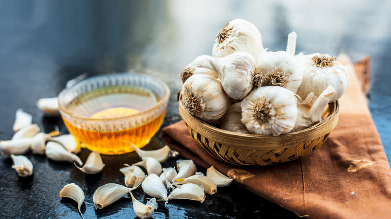 A small basket of garlic bulbs sit beside small bowl of honey