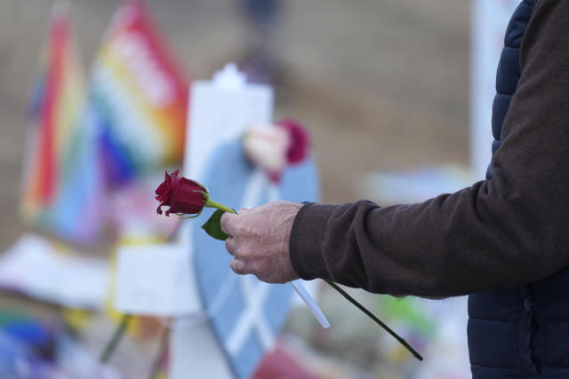 A man places a rose at a cross, part of the makeshift memorial for the victims of a mass shooting at Club Q, a gay nightclub, Wednesday, Nov. 23, 2022, in Colorado Springs, Colo. (AP Photo/David Zalubowski)