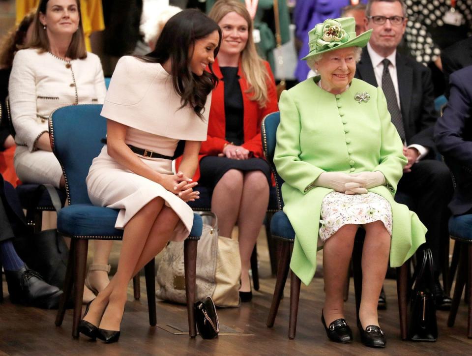 Queen Elizabeth II and Meghan, Duchess of Sussex gesture during their visit to the Storyhouse in Chester, Cheshire in 2018 (AFP via Getty Images)