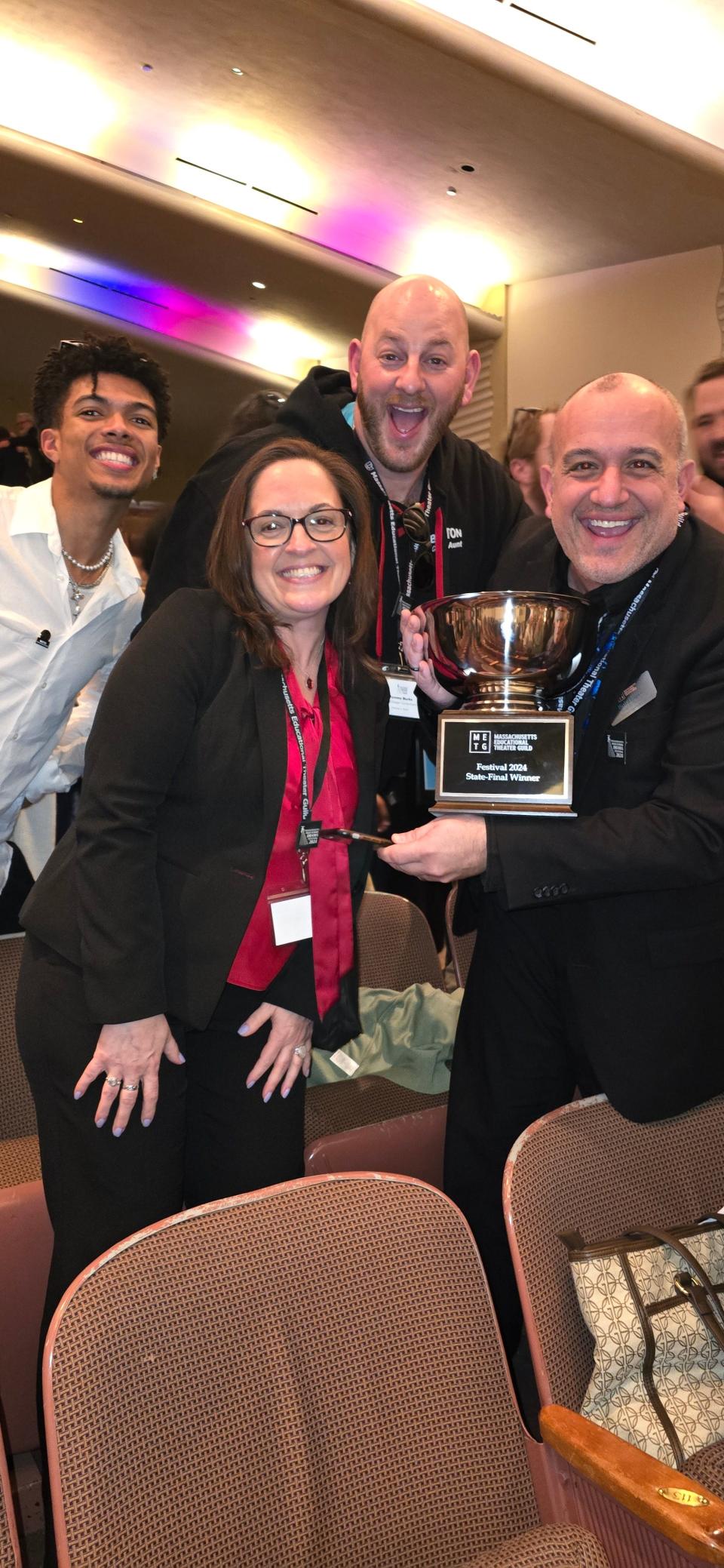 Robert Hogan, director of the BHS Drama Club, holds the first-place trophy after winning the Massachusetts Educational Theatre Guild Competition on Saturday, March 23, 2024. He stands with chaperones and the play's lead actor BHS senior Steven Nascimento.