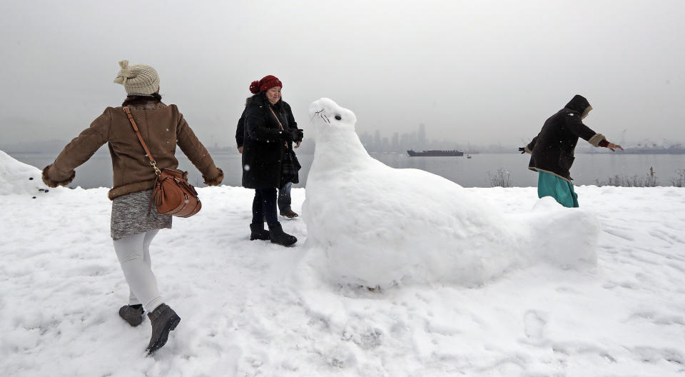 Antoniette Richards, left, and her friends Zusette Rios, center, of Dallas, and Sister Monyen, of the Philippines, explore near a nearly life-sized snow sculpture of a sea lion Monday, Feb. 11, 2019, in Seattle. Schools and universities closed across Washington state and the Legislature cancelled all hearings as the Northwest dealt with snow and ice and prepared for more as a series of winter storms socked the region. (AP Photo/Elaine Thompson)