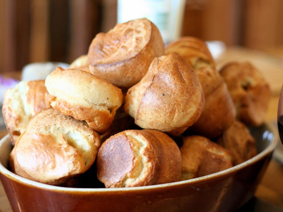 a red bowl of yorkshire puddings next to a glass of red wine