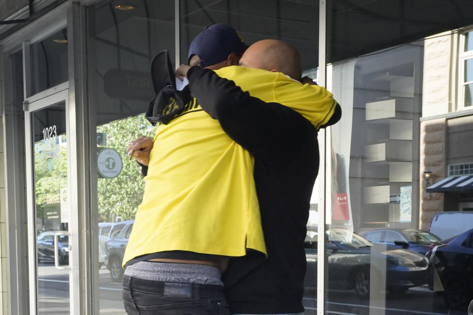 Frank Turner, left, is consoled after Sacramento Police Officers do not allow him to look for his son, who he believes might be one of the six people killed in a mass shooting in Sacramento, Calif. April 3, 2022. (AP Photo/Rich Pedroncelli)