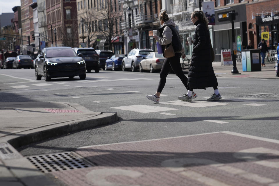 Pedestrians cross the street at the intersection of Washington and 5th in Hoboken, N.J., Thursday, Feb. 22, 2024. This intersection has curb extenders, left, which bumps out the sidewalk near crosswalks, preventing parking near the intersection and increasing visibility for pedestrians. (AP Photo/Seth Wenig)