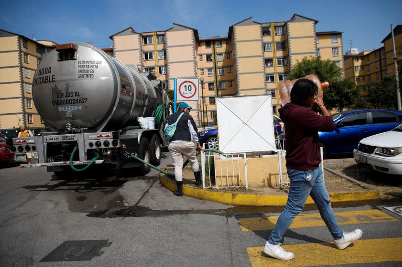 Workers unload water from a truck into a cistern of a housing, in Mexico City