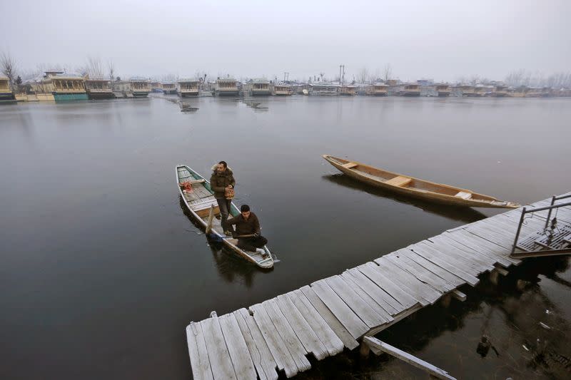 A man rows his boat on the partially frozen Dal Lake on a cold winter morning in Srinagar