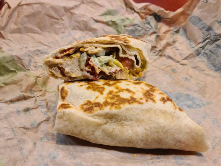 chipotle ranch grilled chicken burrito from taco bell cut in half and resting on a paper wrapper