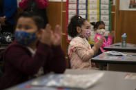 First graders applaud while listening to their teach in a classroom on the first day of in-person learning at Heliotrope Avenue Elementary School in Maywood, Calif., Tuesday, April 13, 2021. More than a year after the pandemic forced all of California's schools to close classroom doors, some of the state's largest school districts are slowly beginning to reopen this week for in-person instruction. (AP Photo/Jae C. Hong)