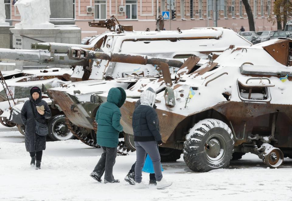 People walk past snow covered, destroyed Russian machinery displayed in Kyiv (EPA)