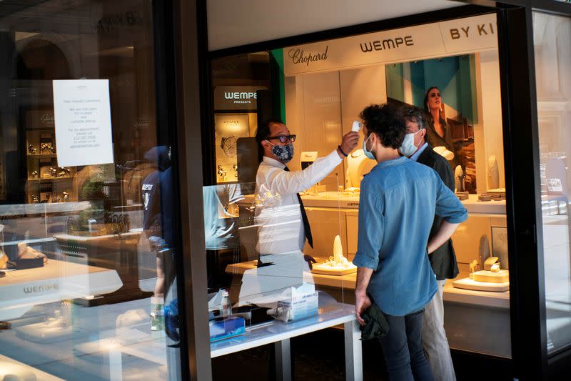 FILE PHOTO: A worker checks the temperature of a client at local store opened for pick up, as phase one of reopening after lockdown begins, during the outbreak of the coronavirus disease (COVID-19), at 5th Avenue, in New York City