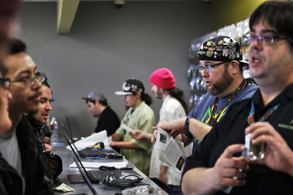 Employees help customers at the crowded sales counter inside Medicine Man marijuana retail store, which opened as a legal recreational retail outlet in Denver on Wednesday, Jan. 1, 2014. Colorado began retail marijuana sales on Jan. 1, a day some are calling "Green Wednesday." (AP Photo/Brennan Linsley)