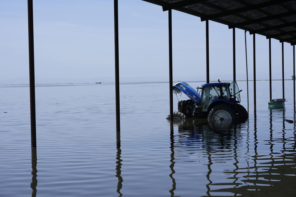 A tractor sits in flood water on the Hansen Ranches property after a series of storms Tuesday, April 25, 2023, in Corcoran, Calif. (AP Photo/Marcio Jose Sanchez)