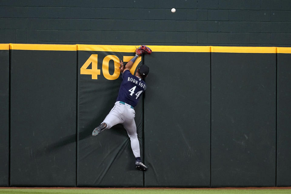Seattle Mariners' Julio Rodriguez slams against the wall after attempting to make a play on a home run ball hit by Texas Rangers' Leody Taveras in the fourth inning of a baseball game, Sunday, Sept. 24, 2023, in Arlington, Texas. (AP Photo/Tony Gutierrez)