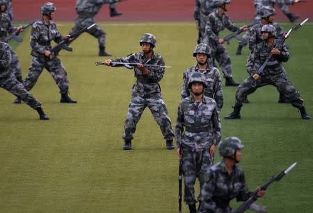 People's Liberation Army (PLA) soldiers practise with guns in a drill during an organised media tour at a PLA engineering academy in Beijing July 22, 2014. REUTERS/Petar Kujundzic