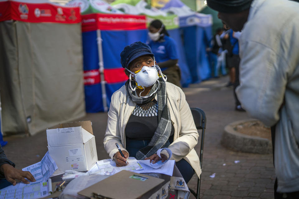 A Johannesburg health official records residents who have been lining up to be tested for COVID-19 as well as HIV and Tuberculosis, in downtown Johannesburg Thursday, April 30, 2020. Thousands are being tested in an effort to derail the spread of coronavirus. South Africa will began a phased easing of its strict lockdown measures on May 1, although its confirmed cases of coronavirus continue to increase. (AP Photo/Jerome Delay)