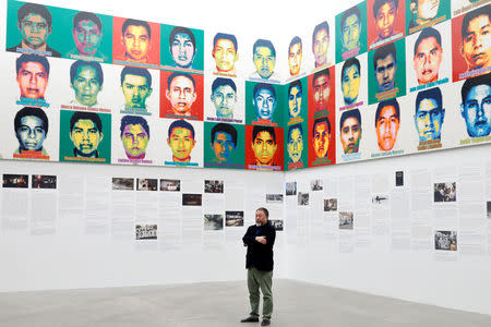 Chinese artist Ai Weiwei poses for photographers in front of portraits of the 43 missing Ayotzinapa College Raul Isidro Burgos students during a photocall for his exhibition "Restablecer Memorias", displayed at the University Museum of Contemporary Art (MUAC) in Mexico City, Mexico, April 11, 2019. REUTERS/Edgard Garrido/Files